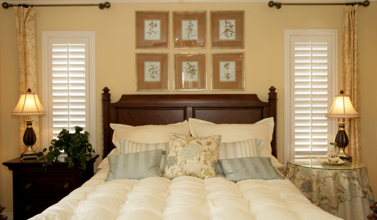 Bedroom with two tall plantation shutters on either side of bed in Destin 